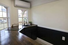 an empty kitchen with wood floors and black counter tops, along with a window that looks out onto the yard