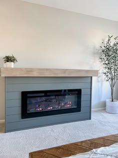 a living room with a fire place in the center and white carpet on the floor