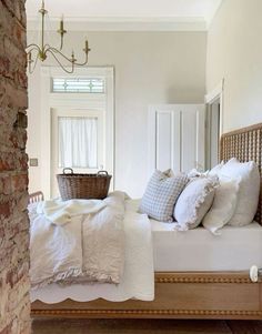 a bed with white linens and pillows in a bedroom next to a brick wall