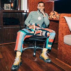 a man sitting on top of a chair in a room with wood floors and walls