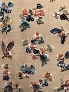 an old embroidered fabric with flowers and birds on it's side, in various colors