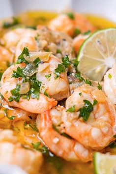 a bowl filled with shrimp and garnish next to a slice of lemon wedge