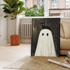 a black cat sitting on top of a ghost canvas in front of a couch and potted plant