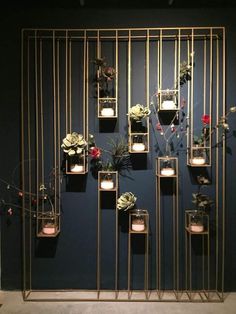 a wall with candles and flowers on it in front of a dark blue wall that is decorated with gold bars