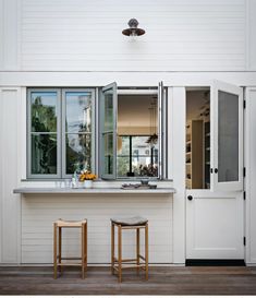 two stools sitting in front of a window on the side of a white building