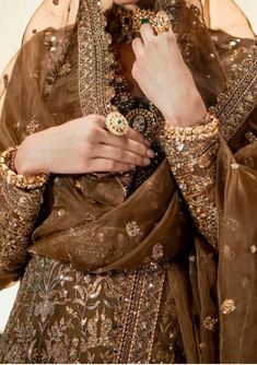 a woman wearing a brown dress and gold jewelry