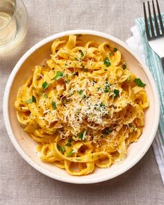 a white bowl filled with pasta and parmesan cheese on top of a table