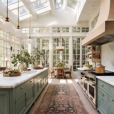 a kitchen filled with lots of green cabinets and counter top space under a skylight