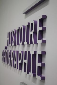 purple and white cut out letters on the wall in an office building, reading'history & photography '