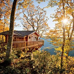 a cabin in the woods with trees surrounding it and sun shining down on the mountains