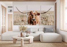 a living room scene with a cow on the wall and a coffee table in front of it