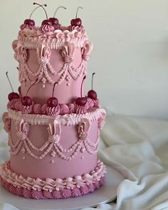 two tiered pink cake with cherries on top