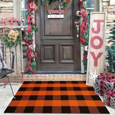 an orange and white checkered rug in front of a door with christmas decorations on it