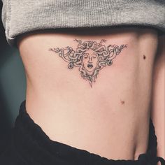 a woman's stomach with an intricate tattoo design on her side ribcage