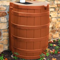 a large plastic barrel sitting next to a brick wall with a cup on top of it