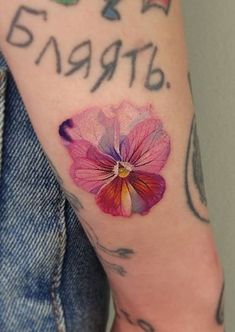 a close up of a person's arm with a flower tattoo on it,