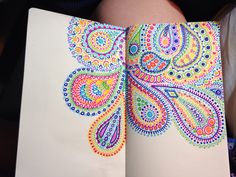 an open notebook with colorful designs on the pages, and a woman's stomach