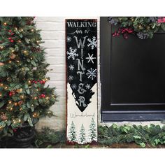 a wooden sign sitting next to a christmas tree