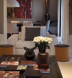 a living room filled with furniture and flowers in a vase on top of a coffee table