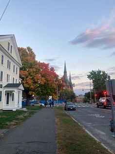 a city street with cars parked on the side and people walking down the sidewalk in front