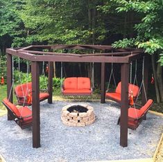 a fire pit with swings and chairs around it in the middle of a gravel area