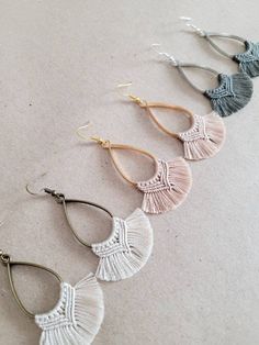 three pairs of earrings with tassels hanging from them on top of a table