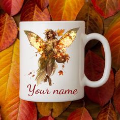 a white coffee mug with an image of a fairy sitting on it's side