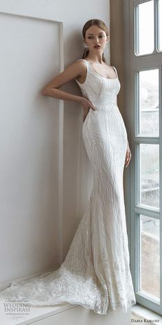 a woman standing in front of a window wearing a wedding dress with an open back