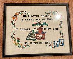 there is a cross - stitch pattern on the wall with words written in it that says, no matter where i serve my guests if they like their kitchen best