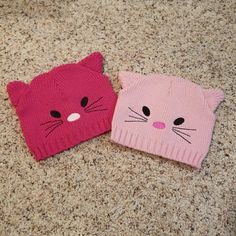 two knitted hats with cats on them sitting on the floor next to each other