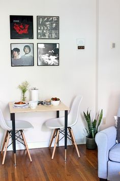 two chairs and a table in a room with pictures on the wall behind them,