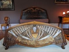 an ornate wooden bed frame in a room with purple walls and paintings on the wall