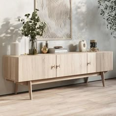 a wooden sideboard with plants and vases on it