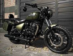 a green motorcycle parked in front of a black garage door on the sidewalk next to a brick building