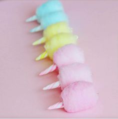 a row of colorful cotton candy sticks on a pink surface