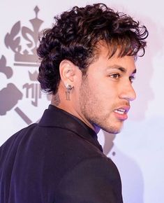 a close up of a person wearing a black shirt and piercings on his ear