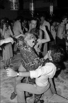 a group of people dancing in a room full of people with their arms around each other