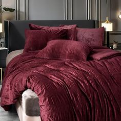 a bed with red sheets and pillows in a bedroom