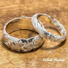 two silver wedding rings sitting on top of a wooden table