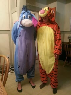 two people dressed in winnie the pooh and tigger costumes standing next to each other