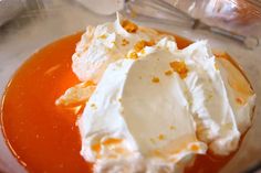 an orange dessert with whipped cream and caramel sauce in a glass bowl on a table