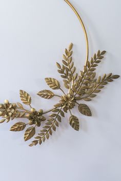 a gold necklace with leaves and flowers hanging from it's side on a white surface