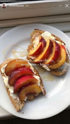 two pieces of bread with sliced peaches and cream cheese on them sitting on a white plate