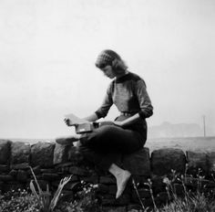 a woman sitting on top of a stone wall