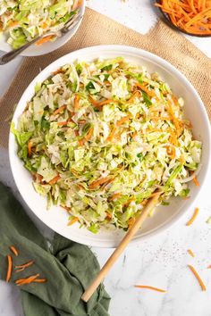 a white bowl filled with coleslaw and carrots on top of a table