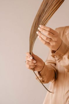 a woman is holding up some brown stalks