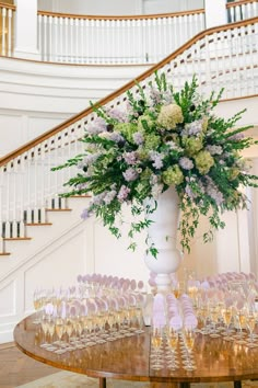 a vase filled with lots of flowers sitting on top of a table next to wine glasses