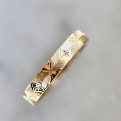 a close up of a gold ring on a white surface with small stars in the middle