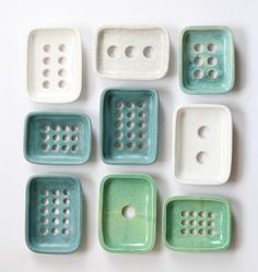 nine green and white ceramic trays with holes in the middle on a white surface