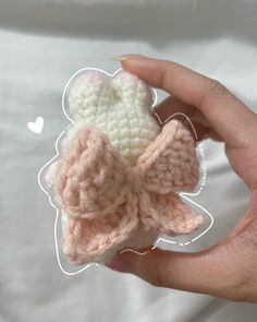 a hand holding a small crocheted bow brooch